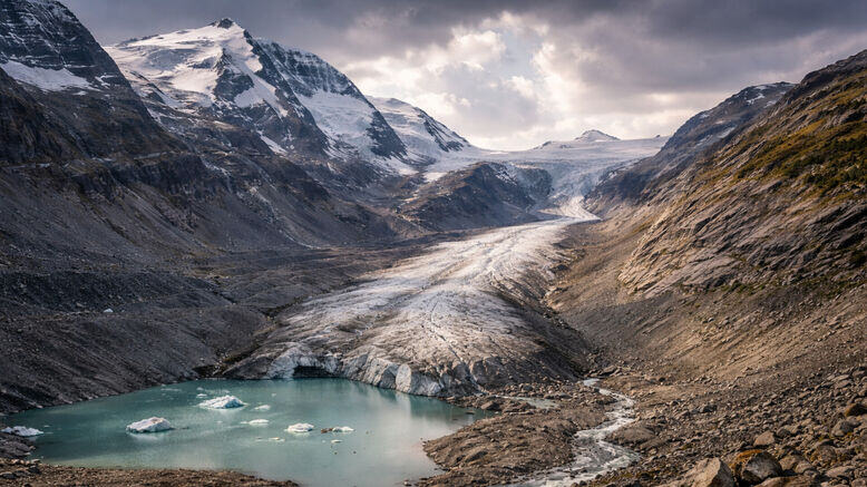ऑस्ट्रिया के आल्प्स पहाड़ों में पीछे हटते हुए विशाल पास्टर्ज़ ग्लेशियर का दृश्य, जहां बर्फ की सफेद परत कम और चट्टानें ज्यादा दिख रही हैं।